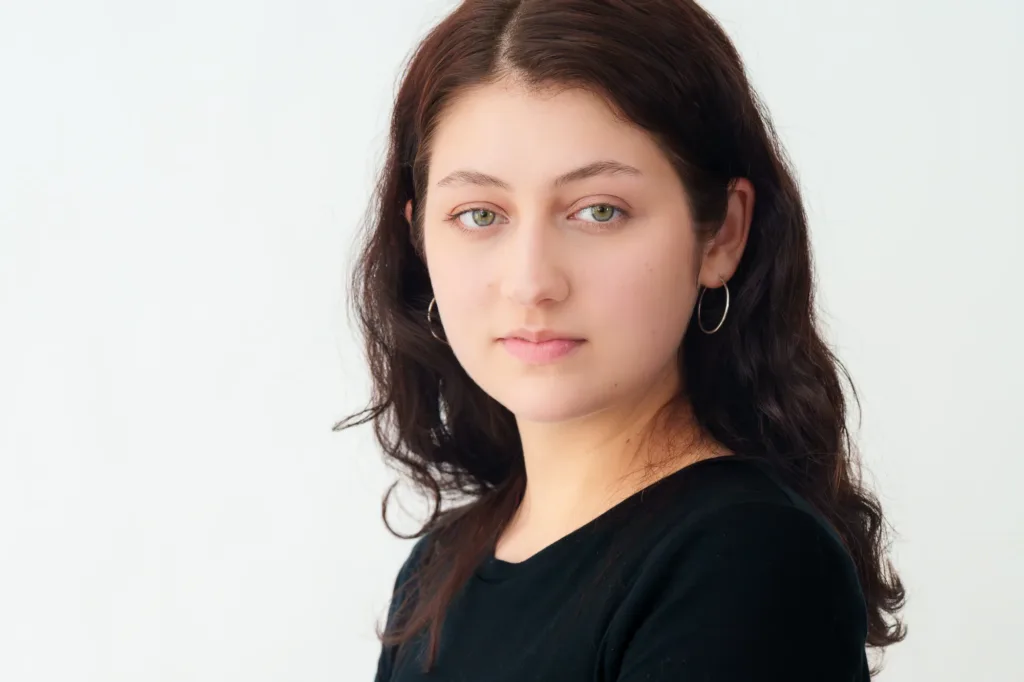 Close-up professional headshot of a woman with soft makeup and hoop earrings, photographed by JG in Tokyo.